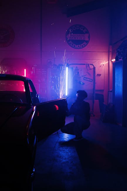 A car mechanic welding a vehicle door in a neon-lit garage with sparks flying.